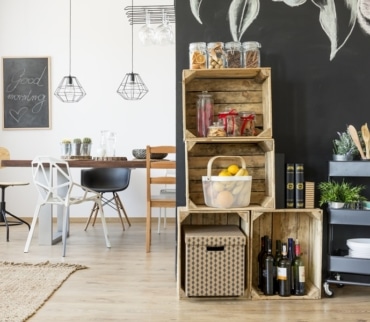 Sistema de almacenamiento sostenible doméstico con cajas de madera reciclada, carrito auxiliar y frascos de vidrio, ideal para mantener el orden con soluciones ecológicas.