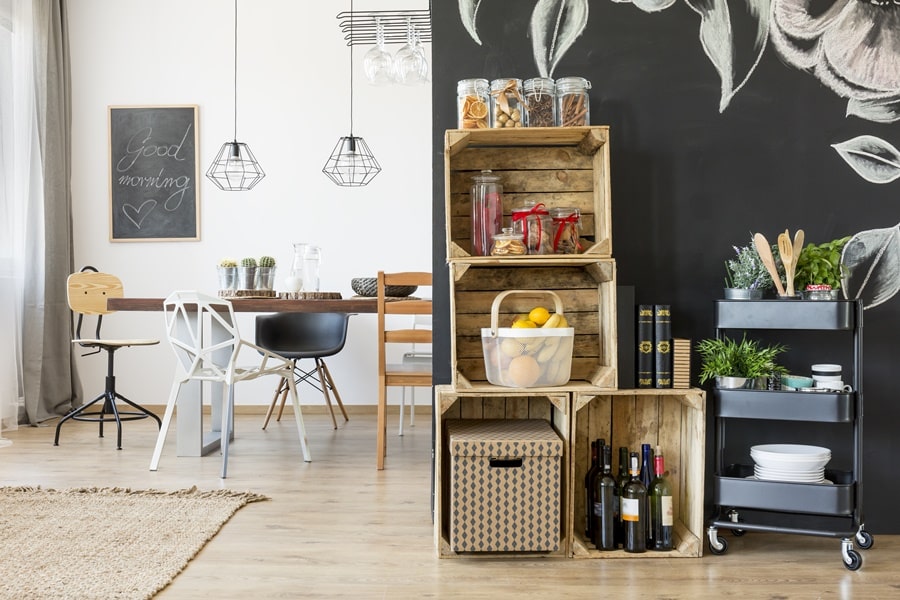 Sistema de almacenamiento sostenible doméstico con cajas de madera reciclada, carrito auxiliar y frascos de vidrio, ideal para mantener el orden con soluciones ecológicas.