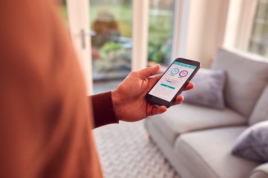 Uso de apps para el hogar en entorno moderno, con móvil en mano mostrando herramientas digitales para organizar tareas y espacios.