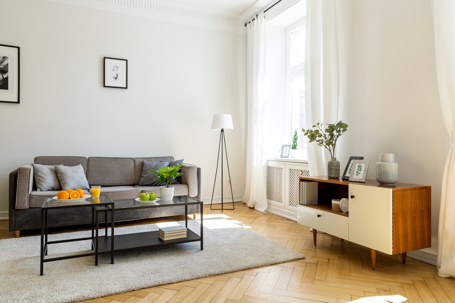 Salón minimalista con sofá gris, mesa con frutas y decoración sencilla, donde la armonía del espacio refleja cómo el orden ayuda a reducir la ansiedad en el día a día.