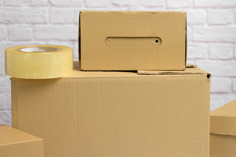 Cajas de cartón con cinta adhesiva sobre fondo claro, listas para almacenar objetos. Material básico para quienes buscan cómo organizar un trastero de forma ordenada y funcional.