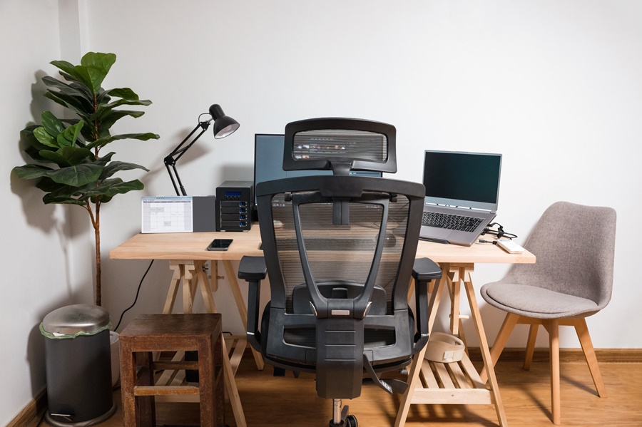 Escritorio con doble pantalla, silla ergonómica y buena iluminación, muestra de organización del teletrabajo desde casa con enfoque en la comodidad y la funcionalidad.