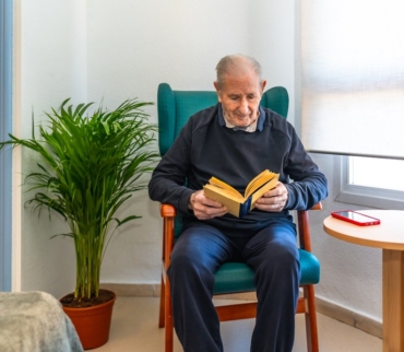 Ejemplo de organización para personas mayores en un ambiente seguro, con silla estable, buena iluminación y zona de lectura sin obstáculos.