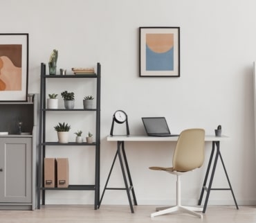 Zona de trabajo organizada con escritorio blanco, estantería vertical con plantas y cajas, y decoración sobria. Ejemplo visual de minimalismo práctico en espacios funcionales.