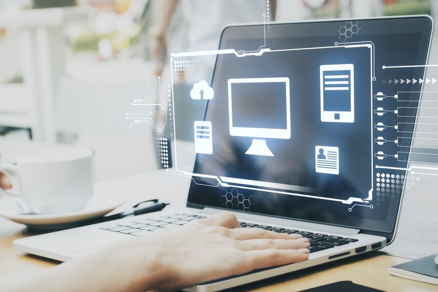 Ordenador portátil con interfaz virtual proyectada sobre la pantalla mostrando iconos de archivos, nube y dispositivos, representando procesos de organización digital en entornos de trabajo conectados.